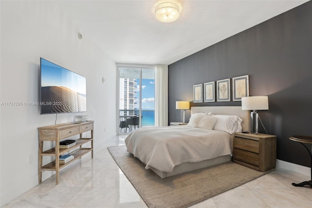 bedroom with baseboards, a wall of windows, and access to exterior