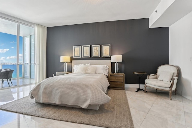 bedroom featuring a water view, access to exterior, expansive windows, and baseboards