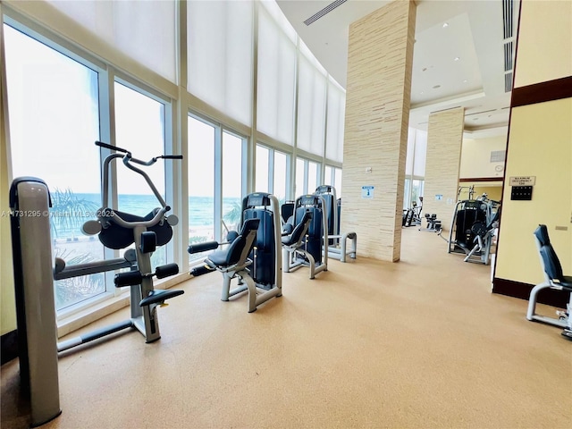 gym with visible vents, a water view, a towering ceiling, and recessed lighting