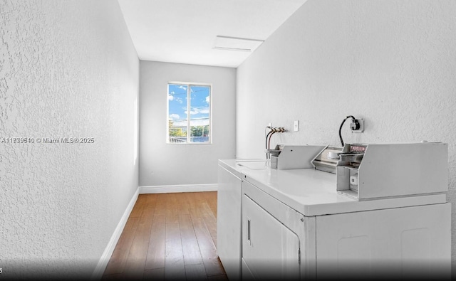 clothes washing area with hardwood / wood-style flooring and washer and dryer