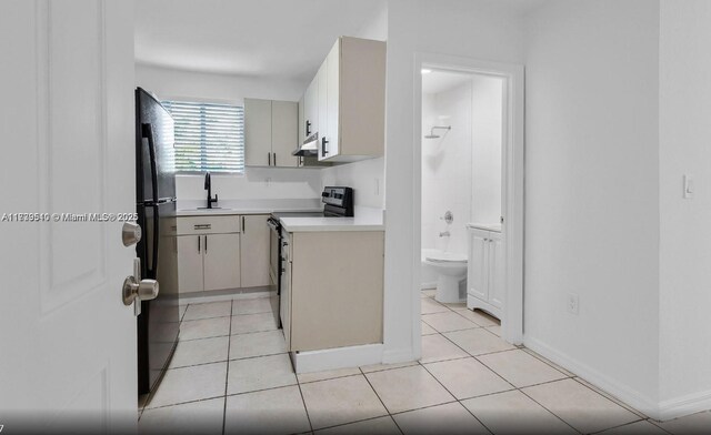 kitchen featuring black fridge, electric range oven, sink, and light tile patterned floors