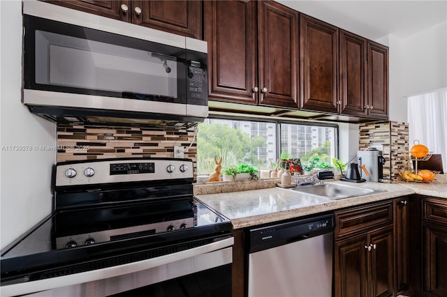 kitchen with dark brown cabinetry, sink, tasteful backsplash, and appliances with stainless steel finishes