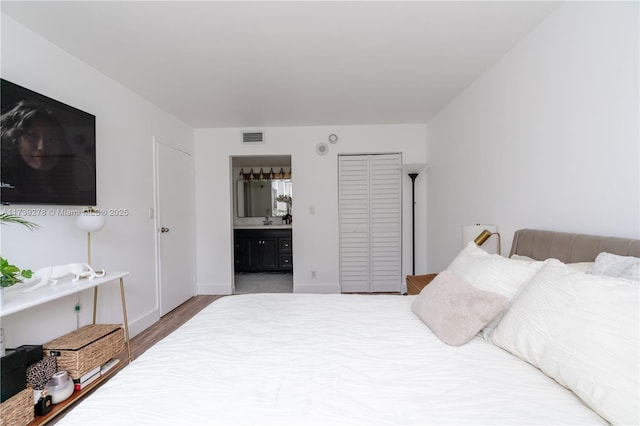 bedroom with ensuite bathroom and hardwood / wood-style floors