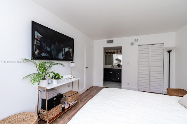 bedroom with connected bathroom, dark hardwood / wood-style flooring, and a closet