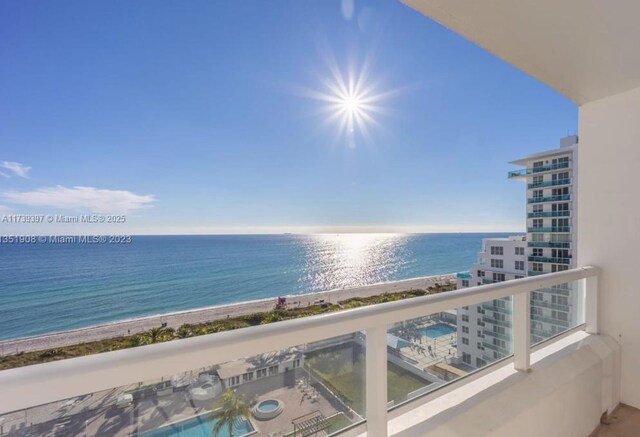 balcony with a water view and a view of the beach