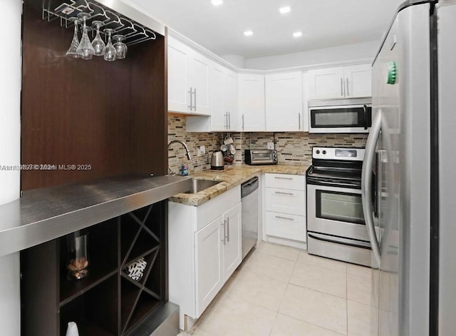 5005 Collins Ave Unit 1212, Miami Beach, FL 33140 - kitchen featuring stainless steel appliances, light tile patterned floors, backsplash, white cabinets, and recessed lighting
