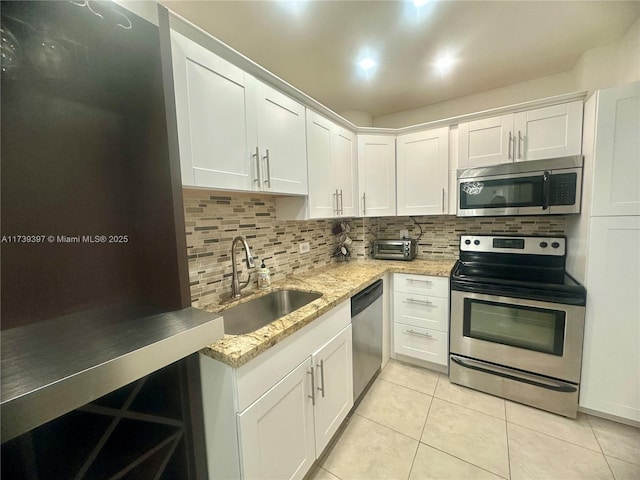 5005 Collins Ave Unit 1212, Miami Beach, FL 33140 - kitchen featuring appliances with stainless steel finishes, a sink, tasteful backsplash, light tile patterned floors, and white cabinets