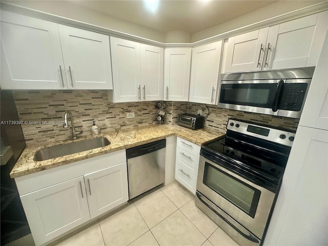 kitchen featuring appliances with stainless steel finishes, white cabinetry, a sink, and backsplash