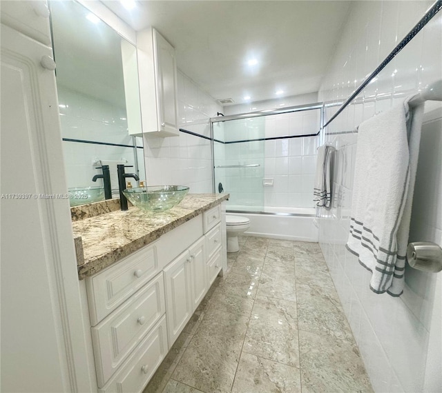 bathroom featuring visible vents, combined bath / shower with glass door, vanity, and toilet