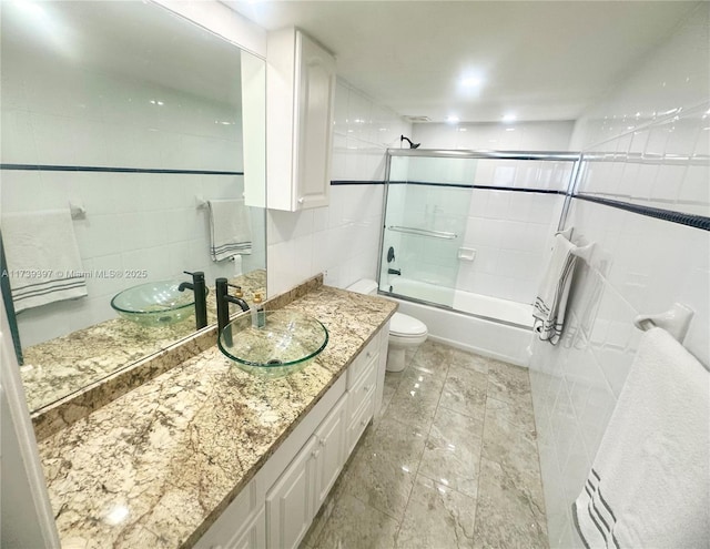 bathroom featuring enclosed tub / shower combo, toilet, tile walls, and vanity