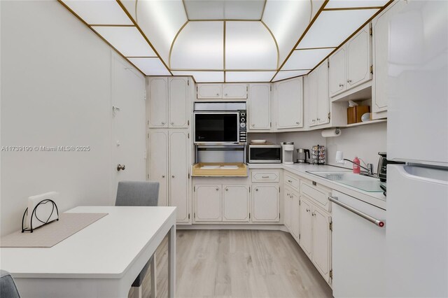 kitchen featuring white cabinetry, sink, wall oven, and light wood-type flooring