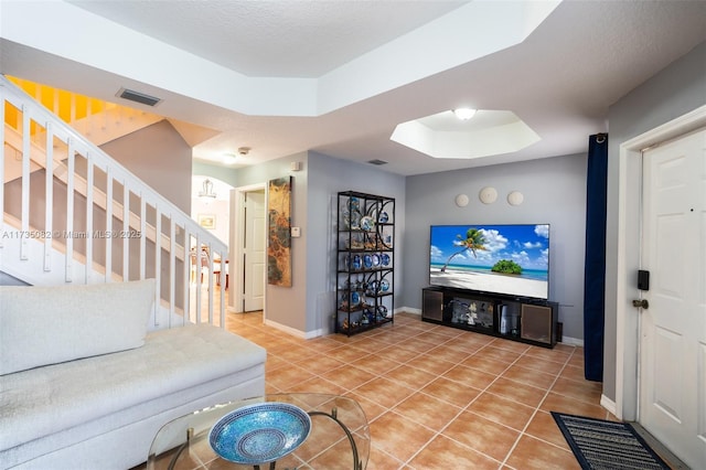 tiled living room featuring a textured ceiling and a tray ceiling