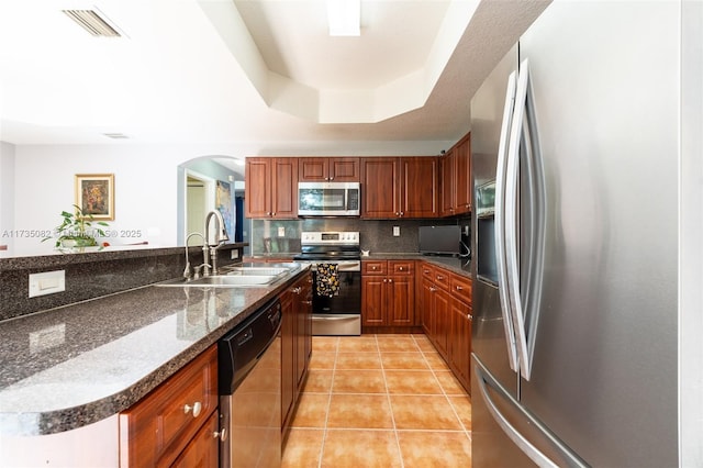 kitchen featuring light tile patterned floors, sink, appliances with stainless steel finishes, decorative backsplash, and a raised ceiling