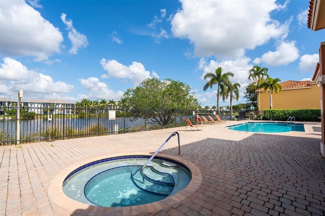 view of swimming pool with a hot tub, a patio, and a water view