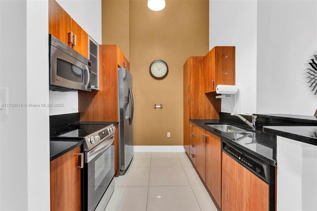 kitchen featuring sink, appliances with stainless steel finishes, a high ceiling, light tile patterned flooring, and dark stone counters