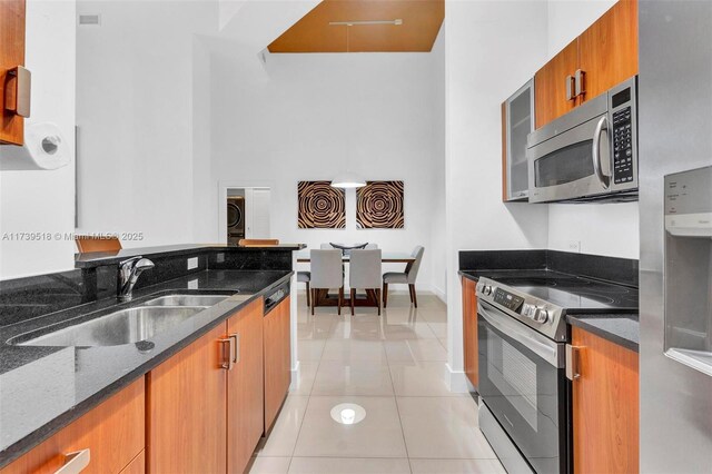 kitchen featuring light tile patterned flooring, washer / dryer, sink, dark stone counters, and stainless steel appliances