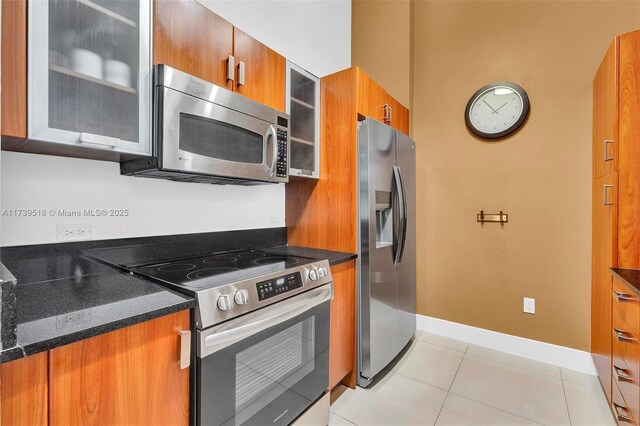 kitchen with appliances with stainless steel finishes, dark stone countertops, and light tile patterned floors