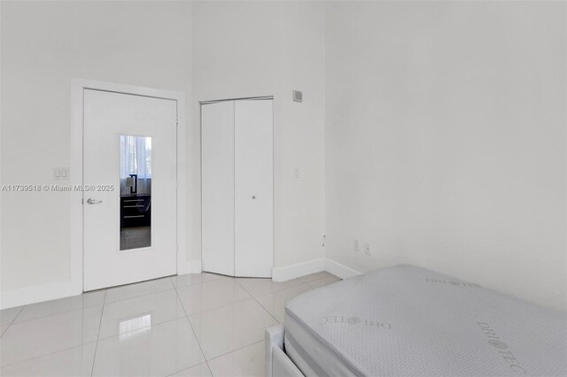 bedroom with light tile patterned floors, a closet, and a high ceiling