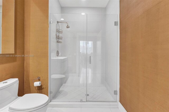 bathroom featuring a shower with door and toilet