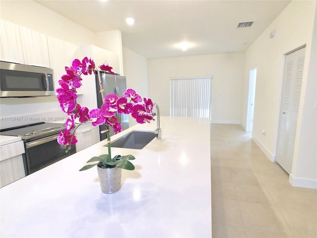 kitchen with light countertops, visible vents, baseboards, appliances with stainless steel finishes, and a sink