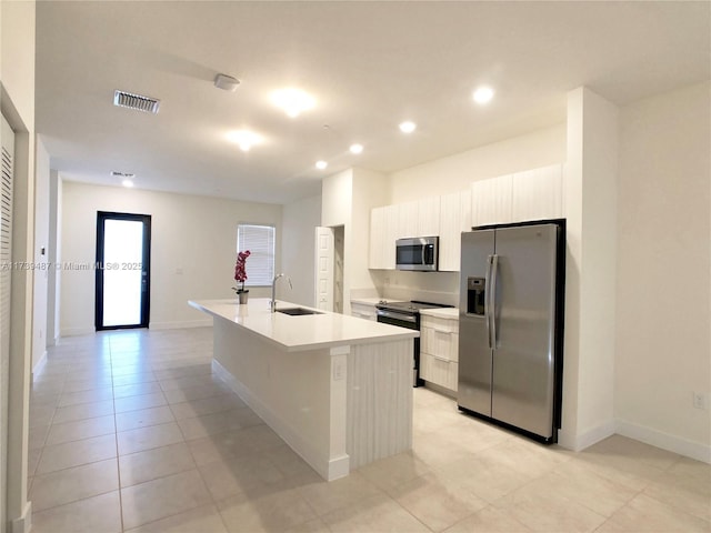 kitchen with light countertops, visible vents, stainless steel appliances, a center island with sink, and a sink
