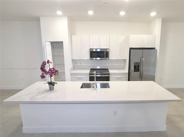 kitchen with modern cabinets, stainless steel appliances, light countertops, and a kitchen island with sink