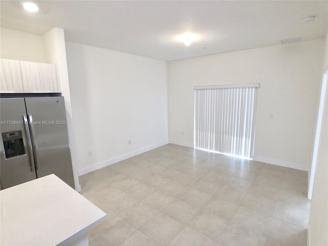 kitchen featuring baseboards, light countertops, recessed lighting, and stainless steel refrigerator with ice dispenser