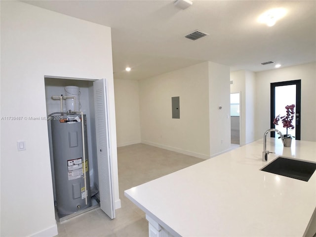 kitchen featuring light countertops, visible vents, electric panel, a sink, and electric water heater