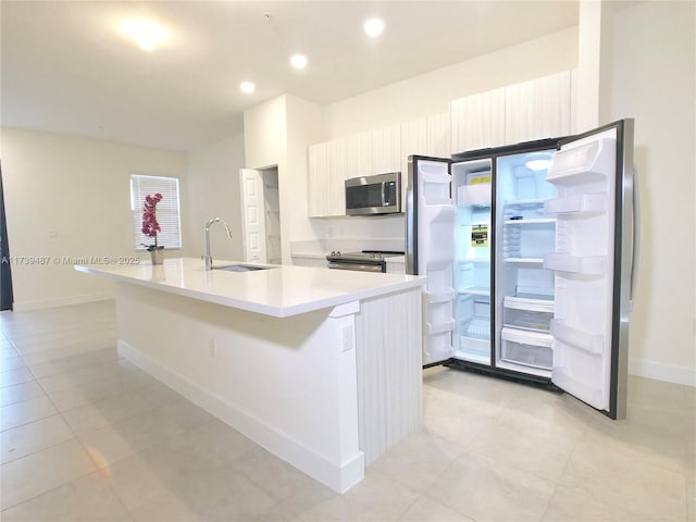 kitchen featuring light countertops, modern cabinets, stainless steel appliances, a center island with sink, and a sink