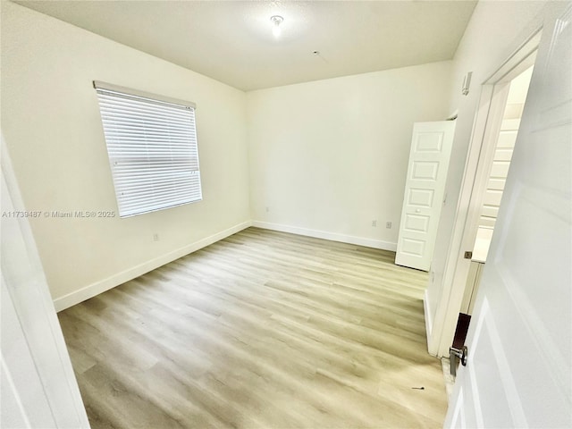 empty room with baseboards and light wood finished floors