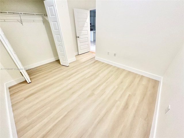 unfurnished bedroom with baseboards, a closet, and light wood-style floors