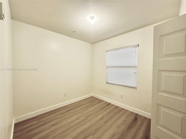 empty room with baseboards, wood finished floors, and a textured ceiling