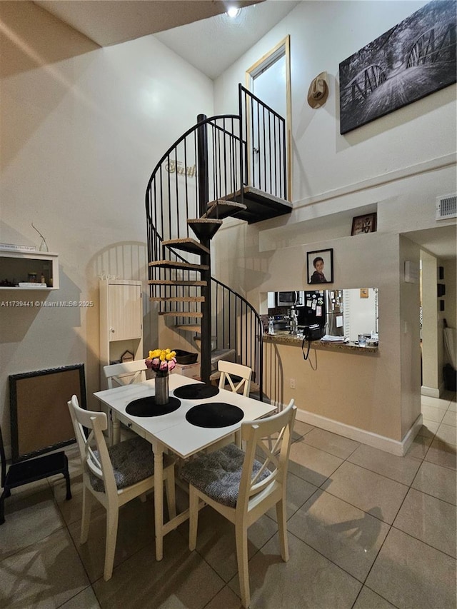 dining room with tile patterned floors and a high ceiling