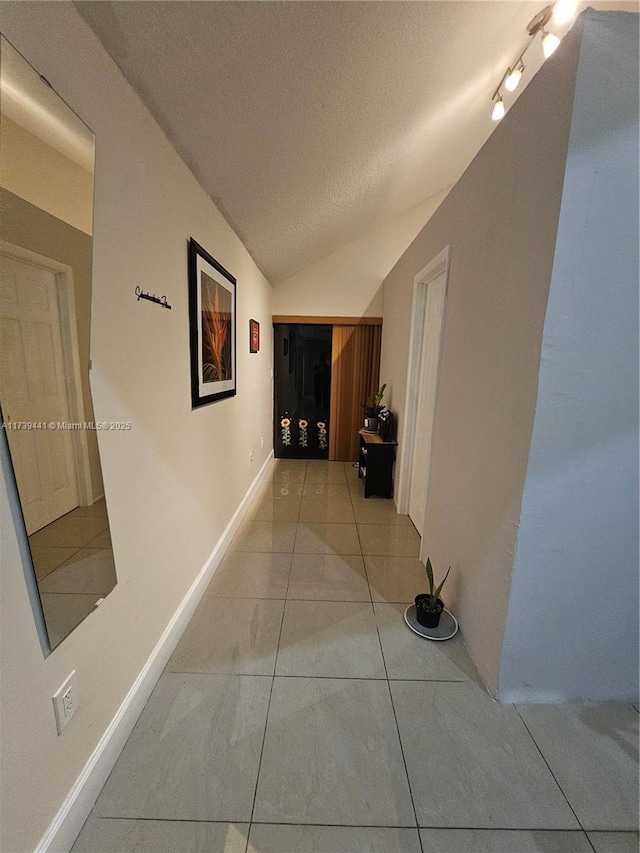 hall with lofted ceiling, a textured ceiling, and light tile patterned floors