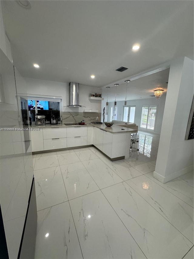 kitchen featuring white cabinetry, black electric stovetop, decorative light fixtures, and wall chimney exhaust hood