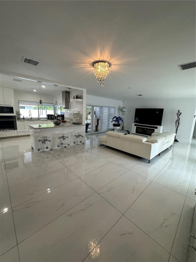 unfurnished living room featuring a notable chandelier and sink