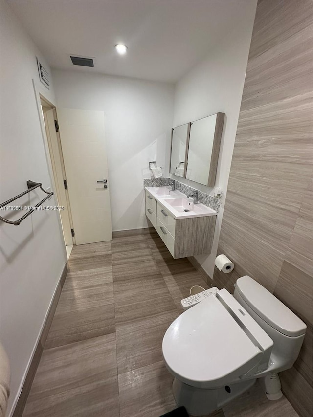 bathroom with vanity, toilet, and tile walls