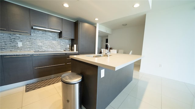 kitchen featuring tasteful backsplash, sink, a kitchen island with sink, black electric stovetop, and light tile patterned floors