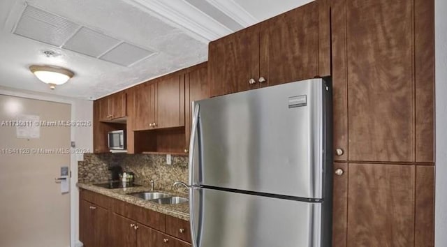 kitchen with light stone countertops, tasteful backsplash, stainless steel appliances, and a sink