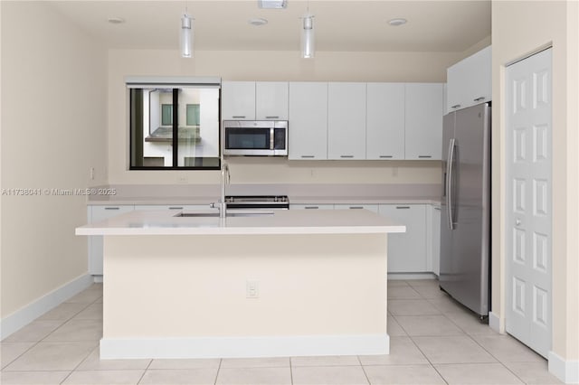 kitchen with appliances with stainless steel finishes, white cabinetry, a kitchen island with sink, and pendant lighting