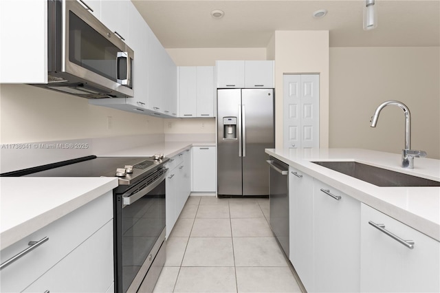 kitchen featuring sink, appliances with stainless steel finishes, white cabinetry, and light tile patterned floors