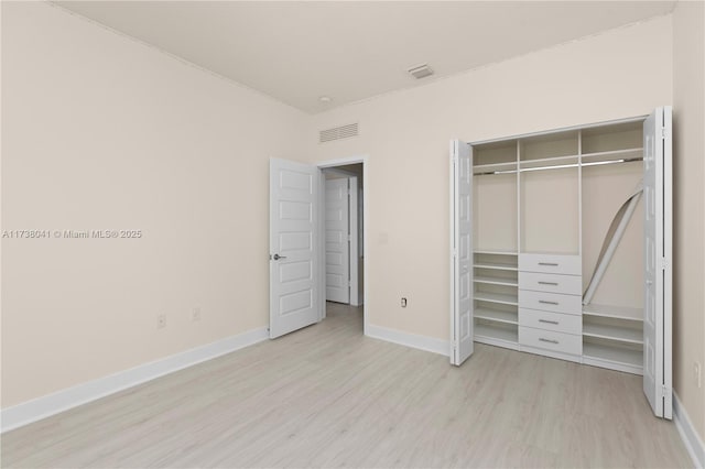 unfurnished bedroom with light wood-type flooring and a closet