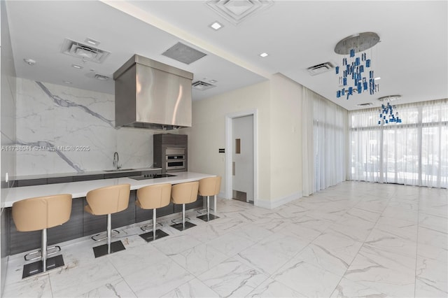 kitchen featuring extractor fan, sink, oven, pendant lighting, and a kitchen breakfast bar