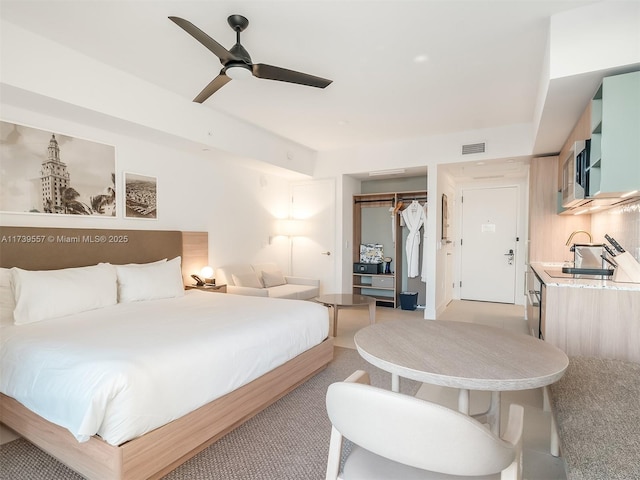 carpeted bedroom with sink, ceiling fan, and a closet