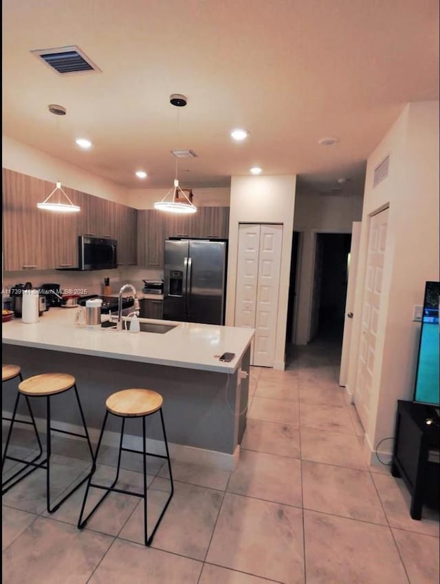 kitchen with appliances with stainless steel finishes, a breakfast bar, pendant lighting, sink, and kitchen peninsula