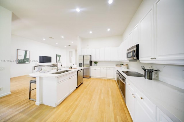 kitchen with appliances with stainless steel finishes, sink, a center island with sink, and white cabinets