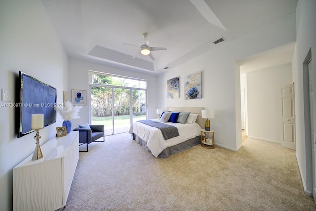 carpeted bedroom featuring a raised ceiling, access to exterior, and ceiling fan