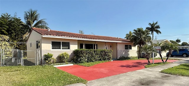 view of front of house featuring brick siding, stucco siding, a front yard, a gate, and fence