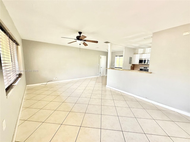 empty room with ceiling fan, decorative columns, baseboards, and light tile patterned flooring