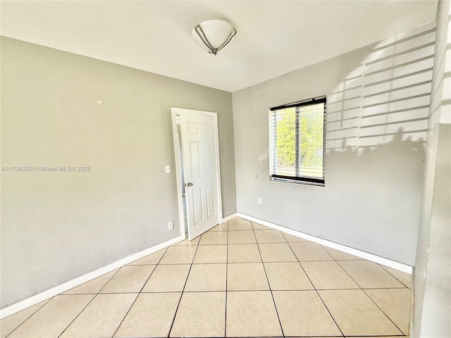 unfurnished room with light tile patterned floors and baseboards